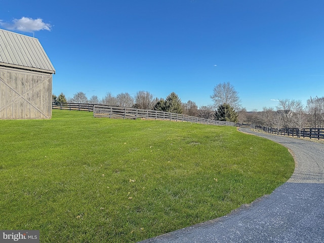 view of yard featuring a rural view, a barn, and fence