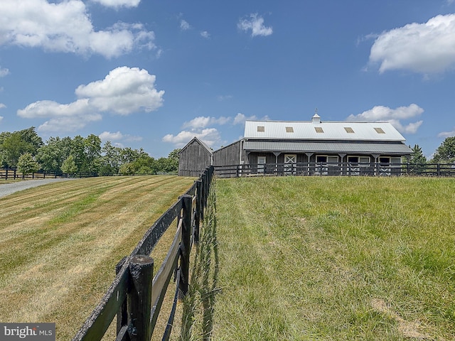 view of yard featuring fence, an outdoor structure, and a rural view