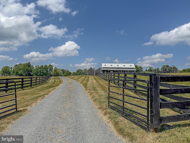 view of street with driveway, a gated entry, and a rural view