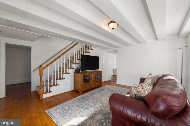 living room featuring wood finished floors, beamed ceiling, and stairs