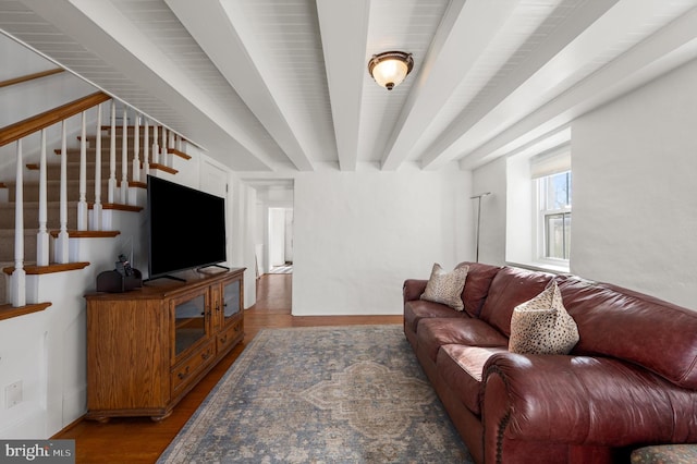 living area featuring stairway, beamed ceiling, and wood finished floors