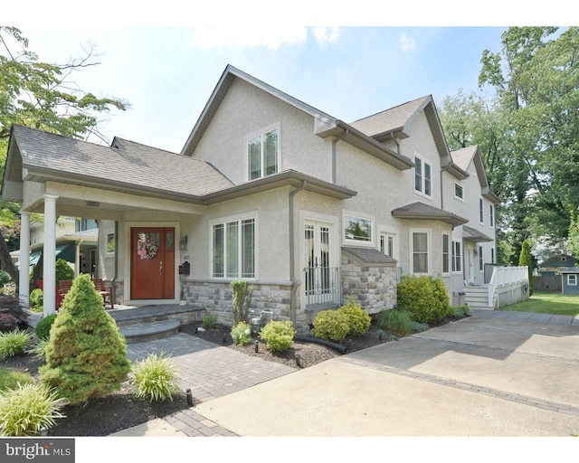 view of front of house with stone siding, roof with shingles, and stucco siding