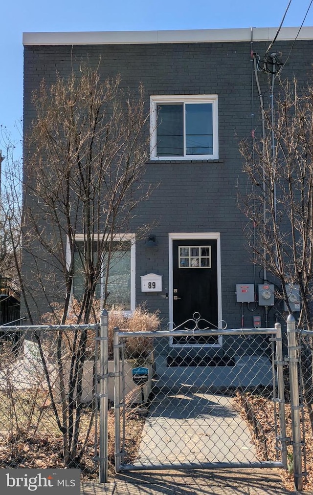 view of front of property with a gate, brick siding, and fence