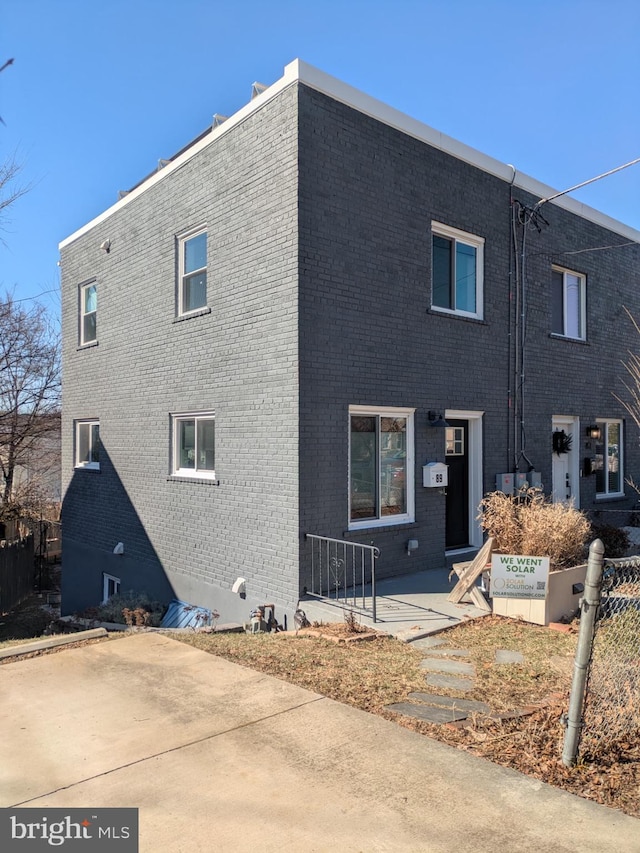 rear view of property featuring brick siding and fence