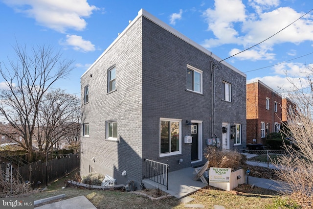 exterior space featuring brick siding and fence