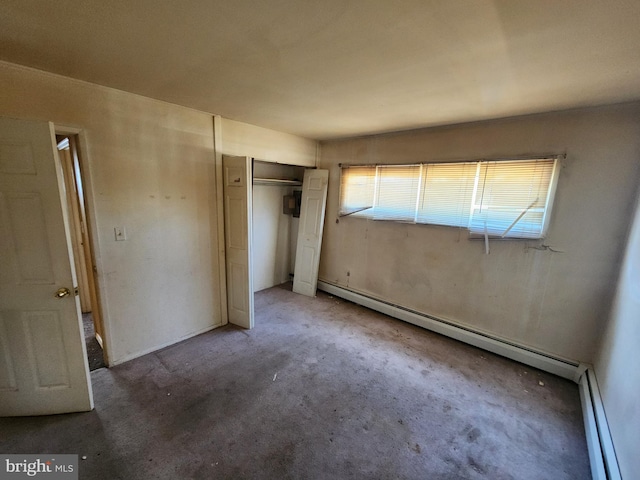 unfurnished bedroom with a closet, a baseboard heating unit, baseboard heating, and carpet flooring