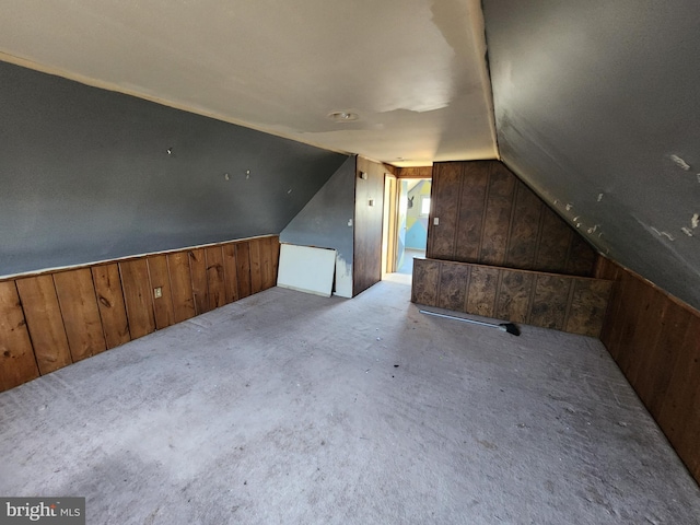 additional living space with lofted ceiling, carpet floors, and wood walls