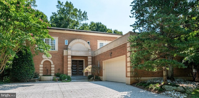 view of front of house featuring decorative driveway, brick siding, and a garage