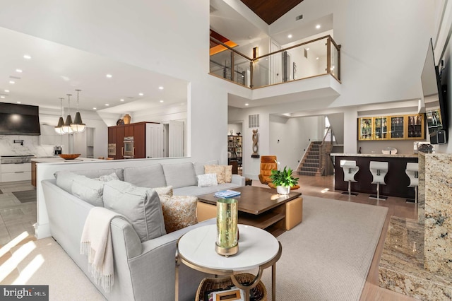 living room featuring visible vents, recessed lighting, stairs, and a high ceiling