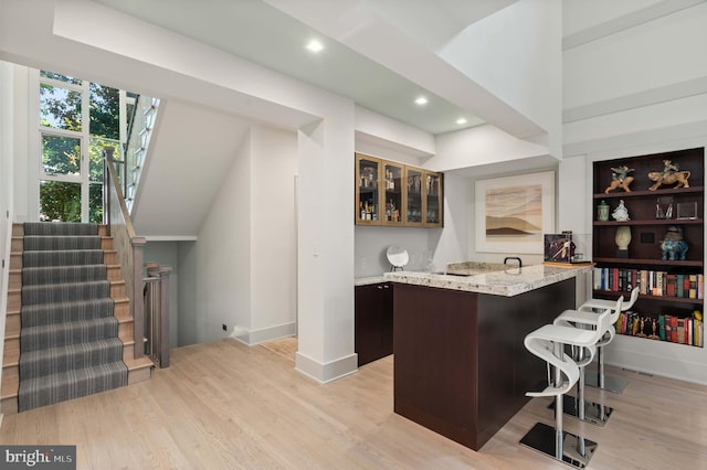 bar featuring baseboards, stairway, recessed lighting, wet bar, and light wood-style floors