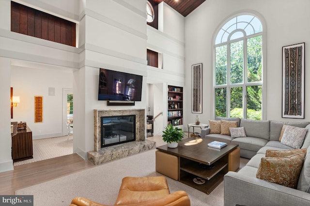 living room featuring baseboards, a high ceiling, wood finished floors, and a high end fireplace