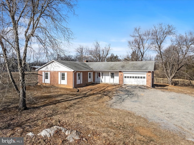 single story home with driveway, a garage, a chimney, and brick siding