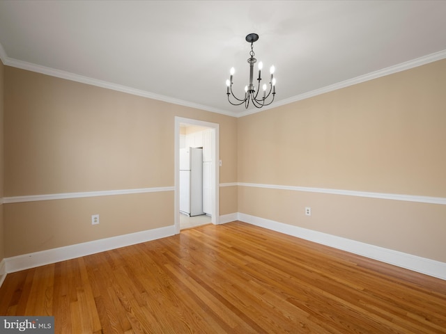 unfurnished room featuring a chandelier, ornamental molding, baseboards, and wood finished floors