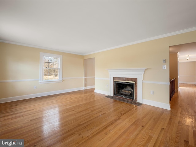 unfurnished living room with crown molding, a fireplace, baseboards, and wood finished floors