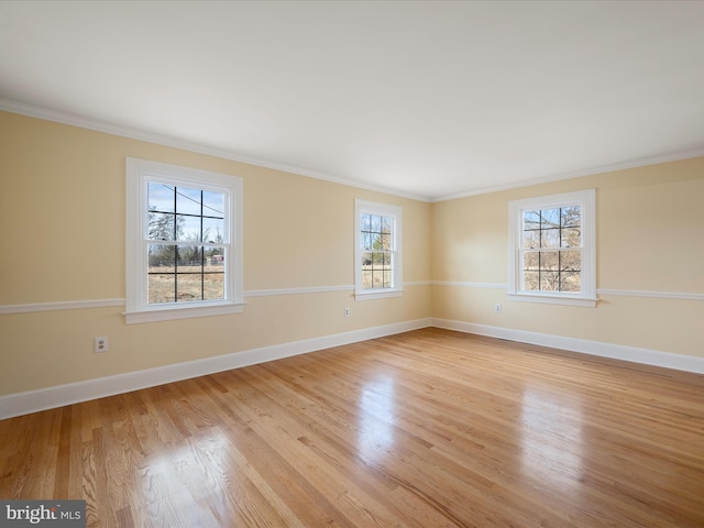 spare room with light wood-type flooring, baseboards, and crown molding