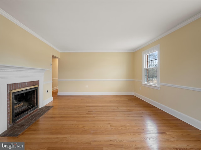 unfurnished living room featuring light wood-style floors, a fireplace with flush hearth, baseboards, and ornamental molding