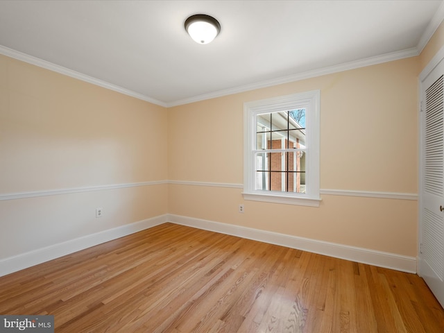 empty room with ornamental molding, light wood-type flooring, and baseboards