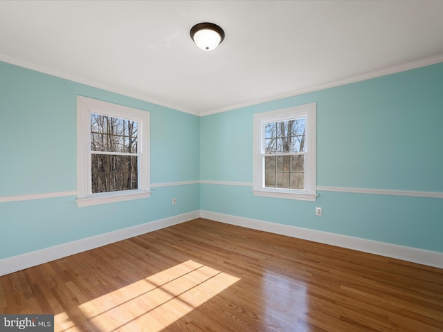 unfurnished room with crown molding, wood finished floors, and baseboards