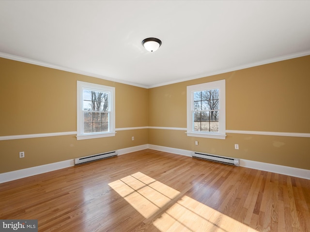 empty room featuring a baseboard radiator, baseboards, and wood finished floors