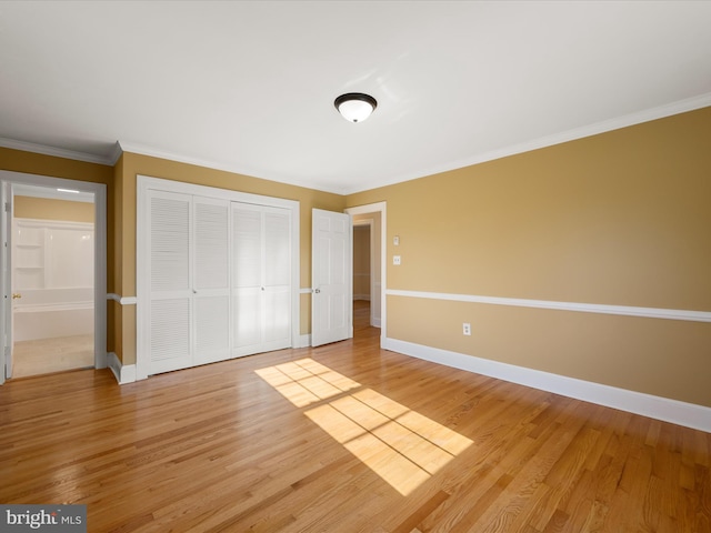 unfurnished bedroom featuring a closet, crown molding, baseboards, and wood finished floors