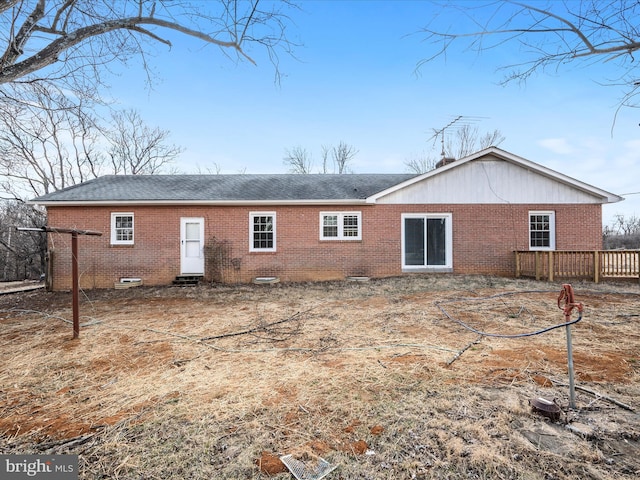 back of house featuring brick siding and a shingled roof