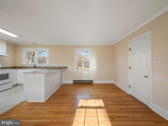 kitchen with a wealth of natural light, white range with electric stovetop, baseboard heating, and white cabinetry