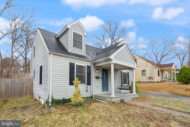 view of front of property with a porch, a shingled roof, and fence