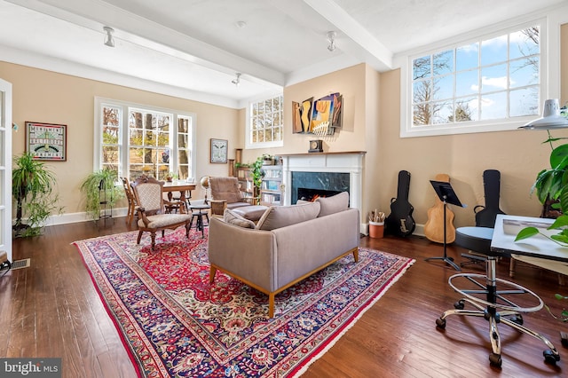 living area featuring hardwood / wood-style floors, a fireplace, baseboards, and beam ceiling