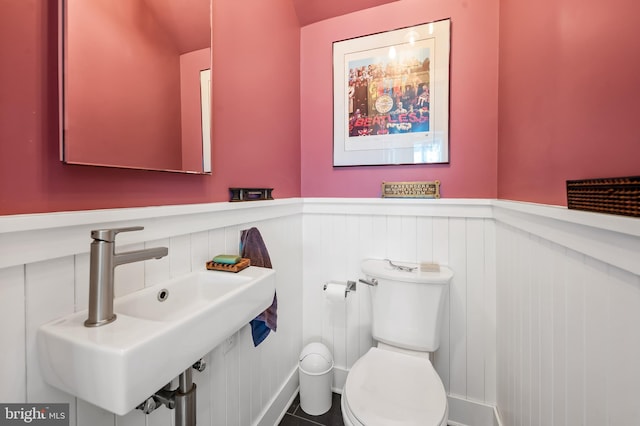 bathroom featuring a wainscoted wall, a sink, and toilet