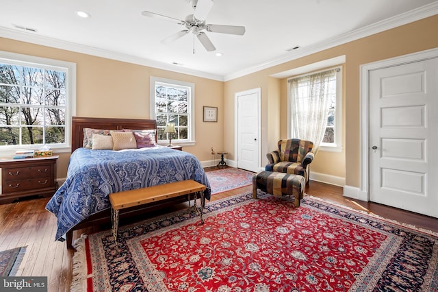 bedroom with wood finished floors, visible vents, and crown molding