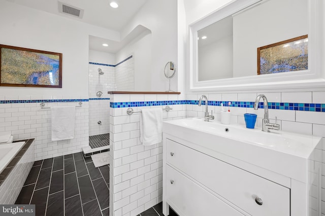 bathroom with recessed lighting, visible vents, vanity, tile walls, and walk in shower