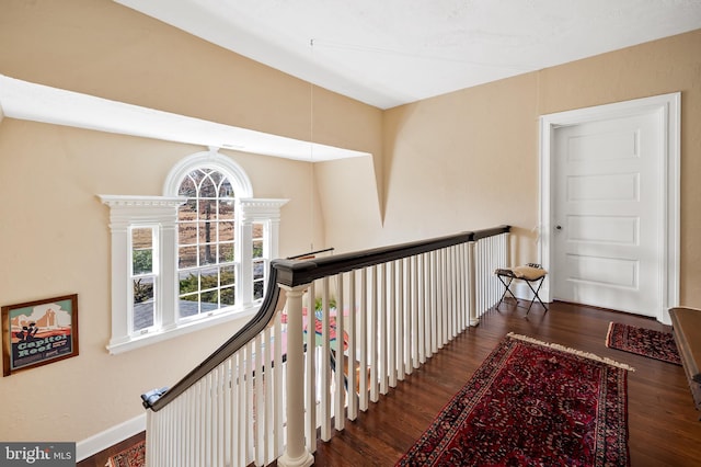 hall featuring wood finished floors, an upstairs landing, and baseboards