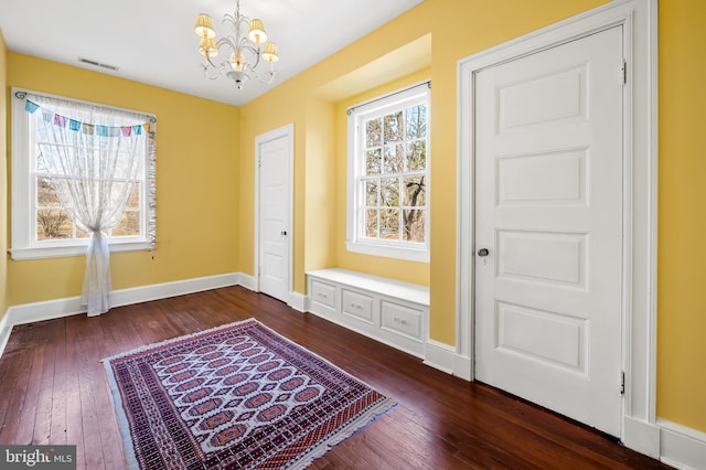 foyer with baseboards, visible vents, dark wood-type flooring, and a notable chandelier