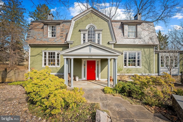 view of front of home with a chimney and fence