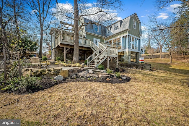 back of house featuring stone siding, a lawn, a deck, and stairs