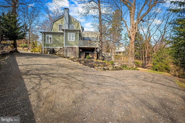 view of front facade featuring a wooden deck, stairway, and a gambrel roof