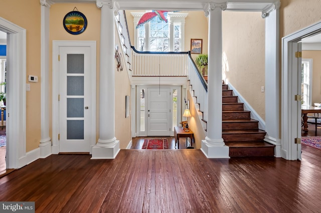 entryway with hardwood / wood-style flooring, a high ceiling, baseboards, stairs, and ornate columns