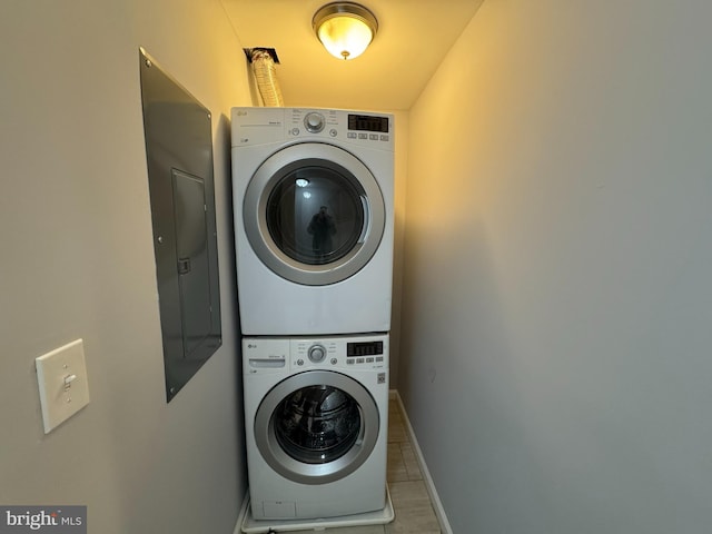 laundry area with stacked washer and dryer, baseboards, electric panel, and laundry area