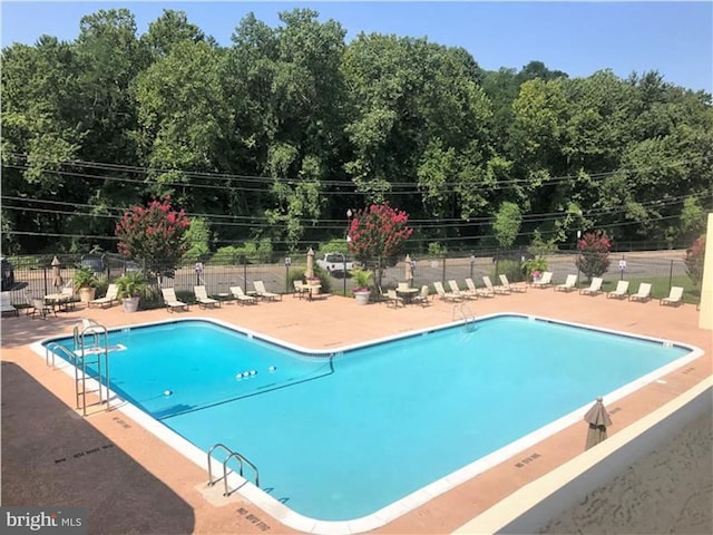 pool with a patio area and fence