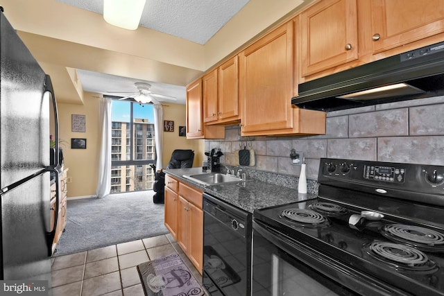 kitchen with tasteful backsplash, a sink, dark stone countertops, under cabinet range hood, and black appliances