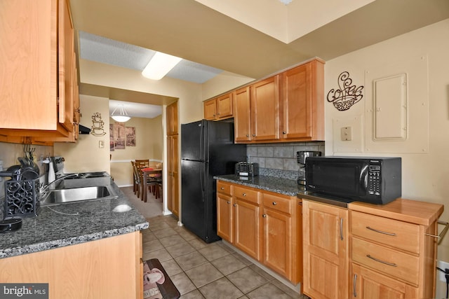 kitchen with light tile patterned floors, a sink, decorative backsplash, dark stone counters, and black appliances