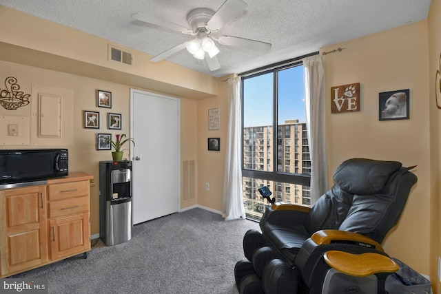 living area featuring visible vents, dark colored carpet, and a textured ceiling