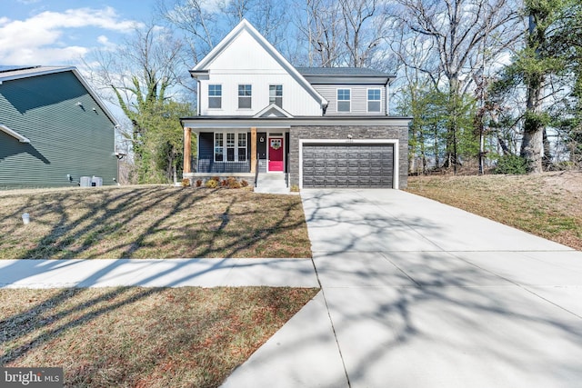 view of front facade featuring driveway, covered porch, stone siding, and a front lawn