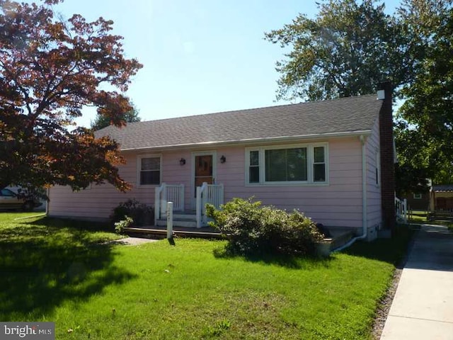 single story home featuring concrete driveway, a front lawn, a chimney, and a shingled roof