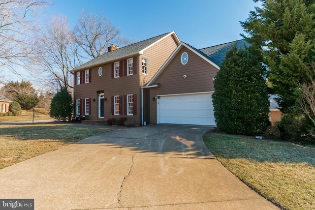 colonial-style house featuring a garage, concrete driveway, a chimney, and a front lawn