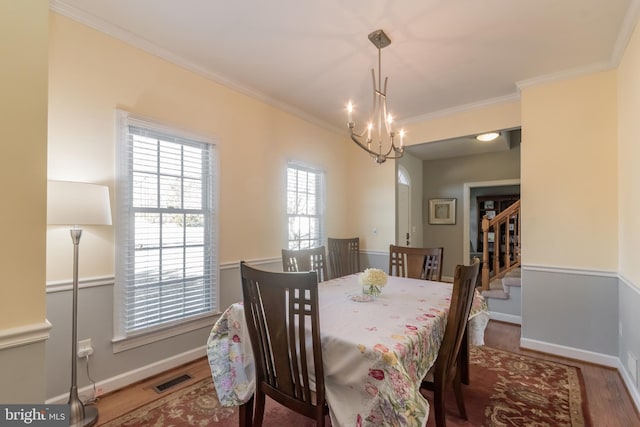 dining room with baseboards, visible vents, wood finished floors, and ornamental molding