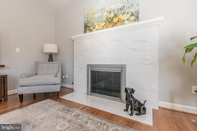 sitting room featuring wood finished floors, a high end fireplace, and baseboards