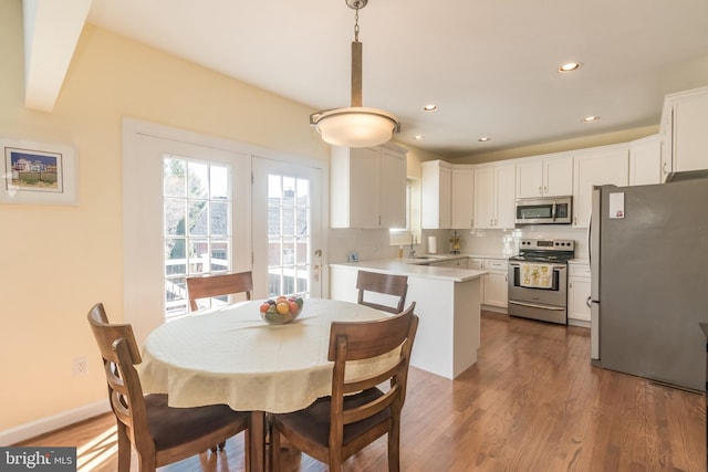 dining area featuring baseboards, wood finished floors, and recessed lighting