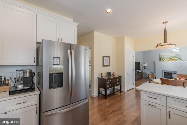 kitchen featuring a premium fireplace, white cabinets, light countertops, stainless steel refrigerator with ice dispenser, and backsplash