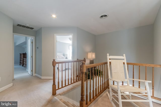 corridor with baseboards, visible vents, carpet flooring, and an upstairs landing